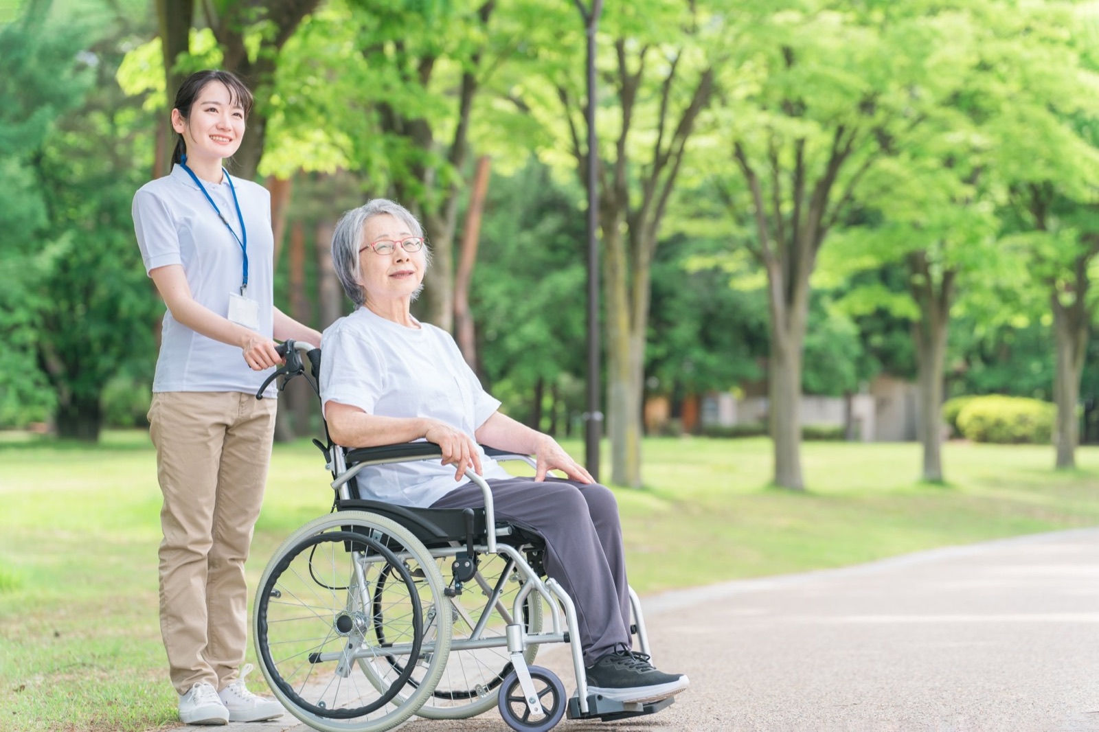 公園を散歩する高齢者と介護士